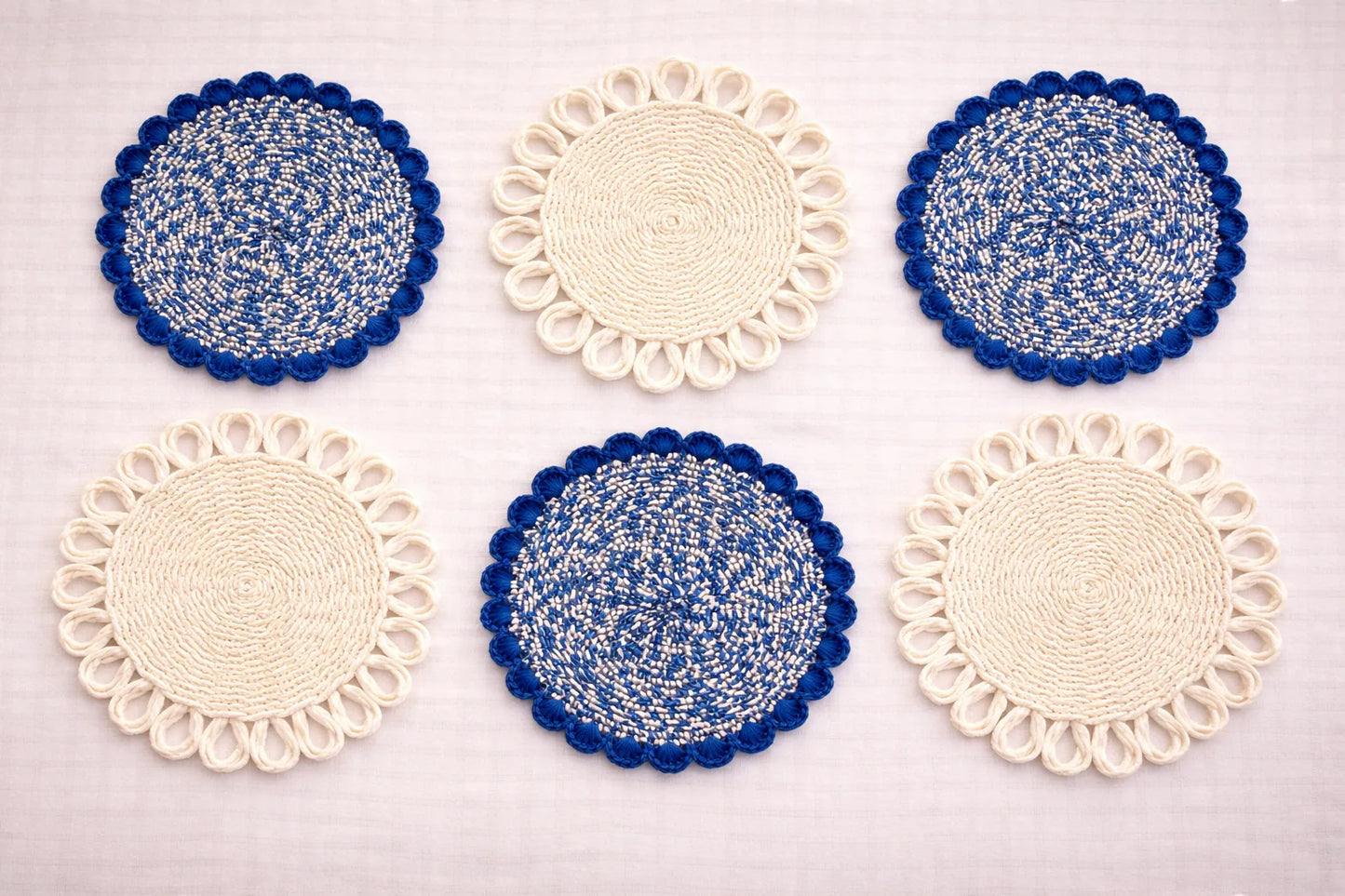 Capri Coastal table setting featuring a blue and white handwoven charger plate with elegant Mediterranean-inspired bohemian accessories in blue and white tones.