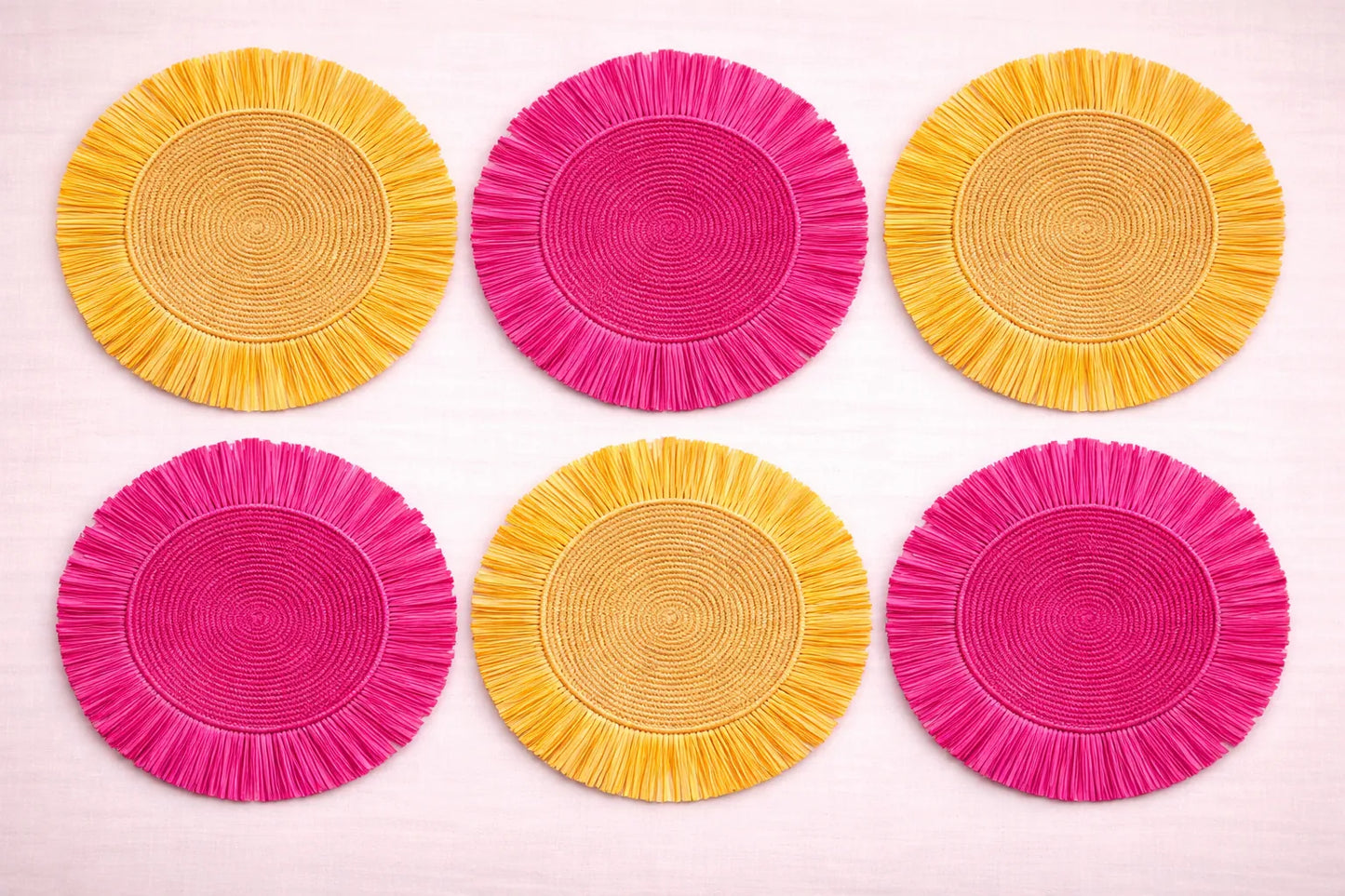 Pink Lemonade table setting featuring a vibrant pink and yellow handwoven charger plate with summery bohemian accessories.