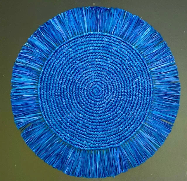 Top-down view of a Soleil Fringe royal blue raffia placemat, showing the vibrant deep blue fringe border and soft handwoven texture for a nautical-themed table.