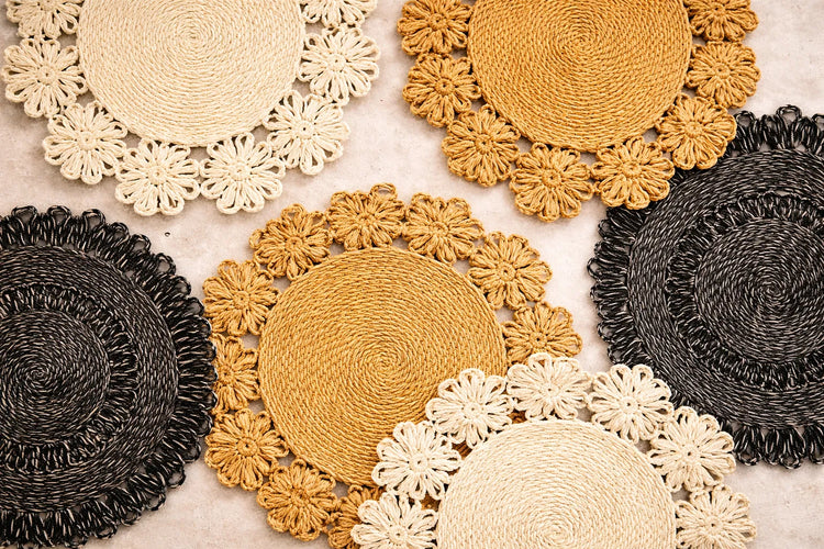 A variety of hand-braided natural abaca fiber charger plates in earthy tones for a sustainable table setting.