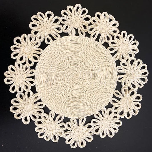 Top-down view of a Chamomile Braided Abaca placemat, featuring layered floral petal braids and a natural cream-colored organic texture.