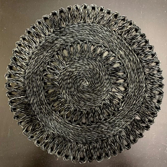 Top-down view of a Midnight Wave black braided abaca placemat, featuring a fluid wave-like braided edge and rich, dark organic texture for a modern luxury table setting.