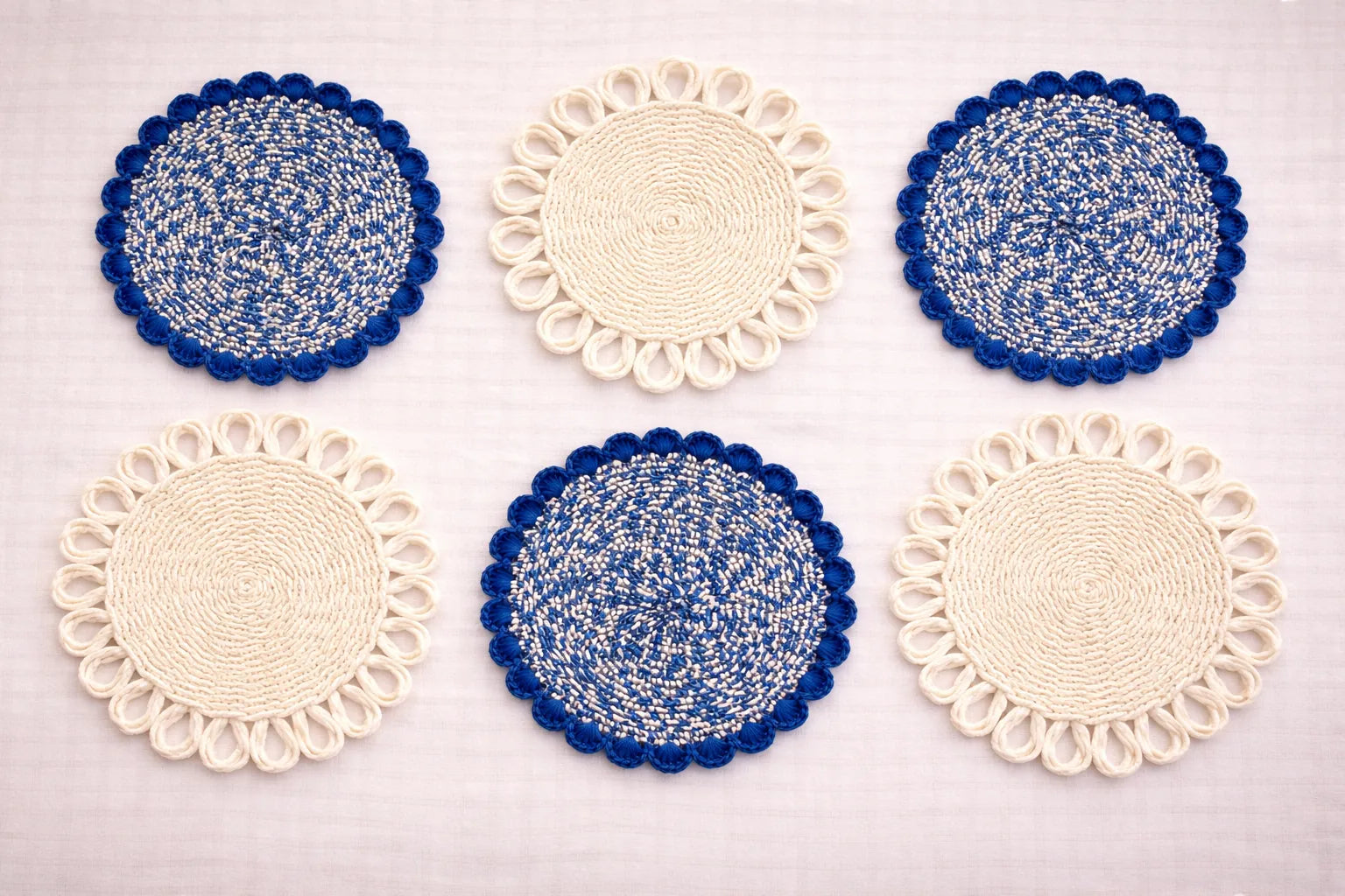Capri Coastal table setting featuring a blue and white handwoven charger plate with elegant Mediterranean-inspired bohemian accessories in blue and white tones.