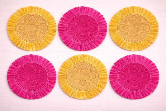 Pink Lemonade table setting featuring a vibrant pink and yellow handwoven charger plate with summery bohemian accessories.