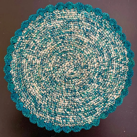 Top-down view of an Emerald Speckle hand-crocheted raffia placemat, showing the rich green multi-tonal weave and soft scalloped edges for a botanical-themed table setting.