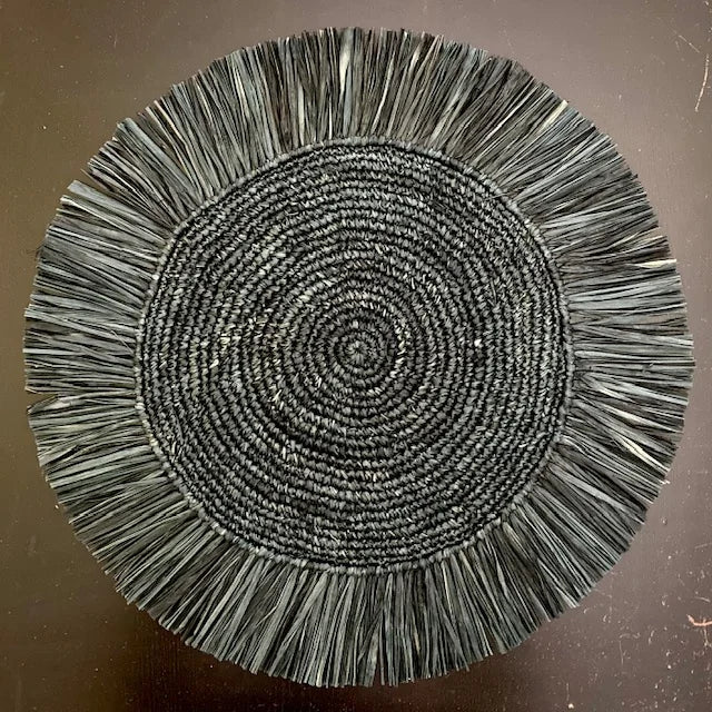 Top-down view of a Soleil Fringe eclipse black raffia placemat, showing the radiant midnight-black fringe border and soft handwoven texture for a modern-themed table.