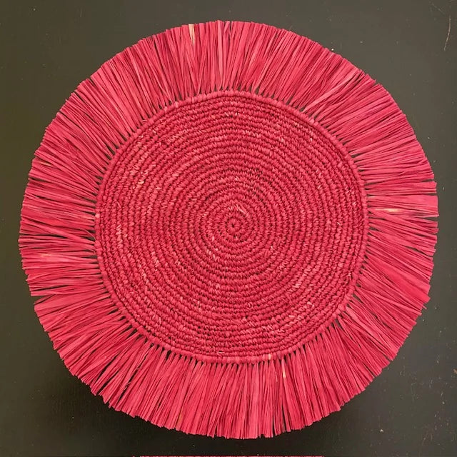 Top-down view of a Soleil Fringe scarlet red raffia placemat, showing the vibrant deep red fringe border and soft handwoven texture for a festive holiday or summer table.