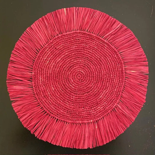 Top-down view of a Soleil Fringe scarlet red raffia placemat, showing the vibrant deep red fringe border and soft handwoven texture for a festive holiday or summer table.