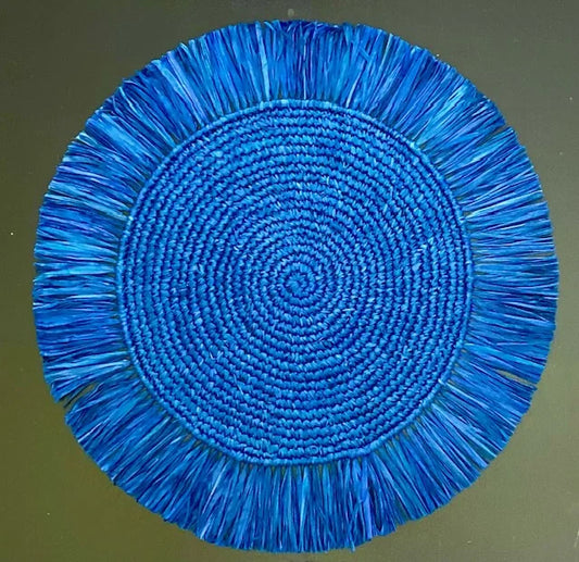 Top-down view of a Soleil Fringe royal blue raffia placemat, showing the vibrant deep blue fringe border and soft handwoven texture for a nautical-themed table.